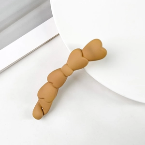 Dettaglio del fermaglio a banana marrone opaco con cinque cuori dal design minimalista