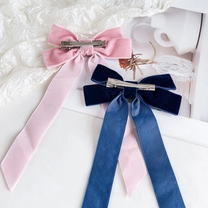 Detail of pink and navy velvet bow hair clips with long satin ribbons and metal duckbill clips