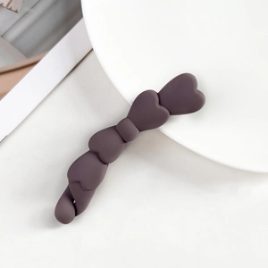 Dettaglio del fermaglio a banana a forma di cuore in resina opaca viola scuro su bianco