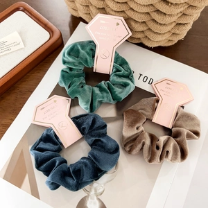 Detailed texture of velvet hair scrunchies with pink diamond tags on a magazine
