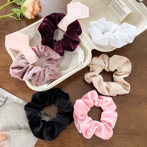 Detailed set of six colorful velvet scrunchies in varied shades on a wooden table