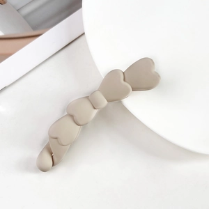 Macro di una clip a banana beige opaco a forma di fiocco con trama a cuore