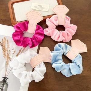 Detail view of velvet scrunchies in four colors with premium branded paper tags