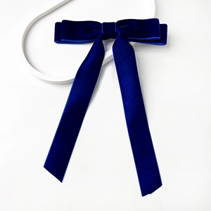 Detailed view of dark blue velvet bow hair clip with elegant long ribbons on white background