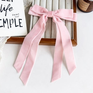 Barrette à cheveux avec nœud en velours rose et longs rubans sur un plateau à bijoux