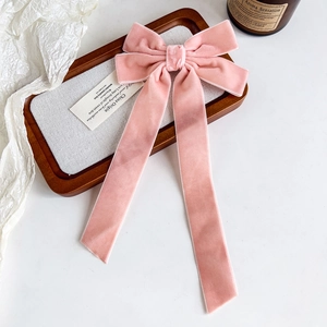 Detail of elegant pink velvet bow hair clip with long ribbons on a wooden tray