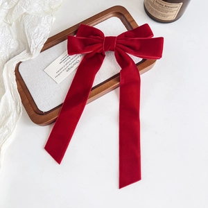 Macro shot of large red velvet bow hair clip with ribbons on a textured display tray