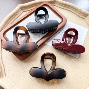 Détail de pinces à cheveux en forme de cœur en noir mat, écaille et rouge bordeaux