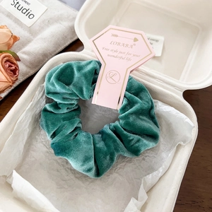 Detail of dark green velvet scrunchie in premium paper box with dried rose decoration