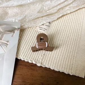Gros plan d'une pince à cheveux rugby avec texture mate marron sur tissu tissé