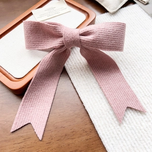 Gros plan d'une barrette à cheveux nœud rose tricoté avec ruban sur plateau bois