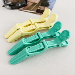 Detail of cream and mint green alligator hair clips with non-slip texture and double hinges