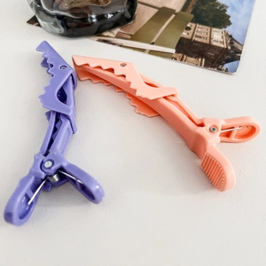 Detail view of light purple and orange crocodile hair clips with matte finish texture