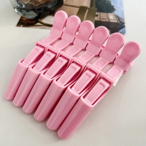 Close-up of six pink salon hair clips with non-slip handles for hair styling