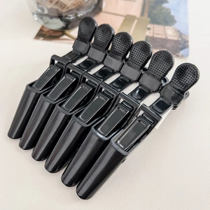 Close-up of six professional black crocodile hair clips with non-slip texture for styling