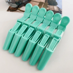 Close-up of six mint green alligator hair clips for professional styling and sectioning