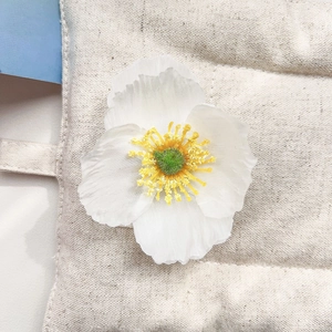 Détail d'une fleur de frangipanier en tissu blanc avec centre jaune sur sac en toile