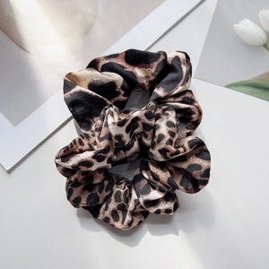 Close-up of leopard print satin hair scrunchies on a minimalist decorative background