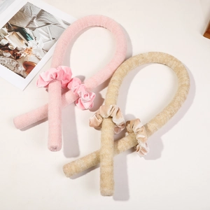Détail à plat des bigoudis sans chaleur en tricot rose et beige avec chouchous en velours