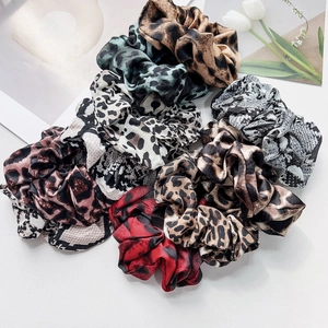 Collection of satin hair scrunchies with leopard and snake skin animal prints on white surface