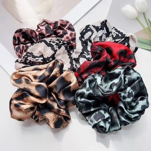 Detail showing four assorted leopard and snake print satin scrunchies with white tulips