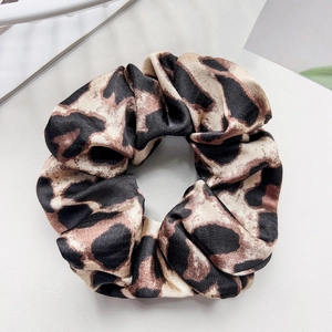 Macro detail of elegant leopard print satin scrunchie with silky texture and folds