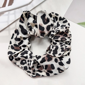 Close-up of leopard print hair scrunchie with soft fabric texture and elegant pleated details