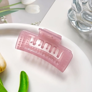 Détail d'une pince à cheveux rectangulaire rose translucide dans un décor élégant