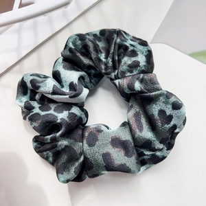 Detailed view of leopard print silk satin scrunchie in teal and black pattern