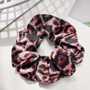 Macro detail of leopard print satin hair scrunchie with silky luster on white texture