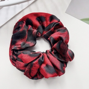 Detailed view of large leopard print scrunchie in red and black silky fabric