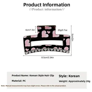 Detail view of large black hair claw clip with pink hearts and size specifications