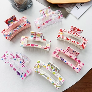 Flat lay of stylish acrylic hair claws with colorful heart prints and romantic text
