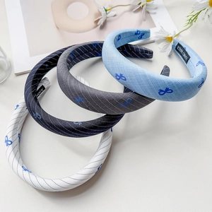 Close-up of wide padded sponge headbands with blue butterfly patterns and handmade label