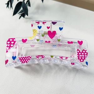Detail view of heart-patterned acrylic hair claw clip with Love prints and metal spring