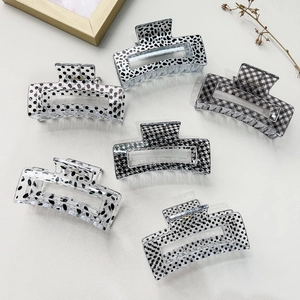 Detailed view of six square hair claws with monochrome patterns including houndstooth and dots
