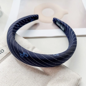 Detail of blue padded headband with embroidery textures and a handmade interior label