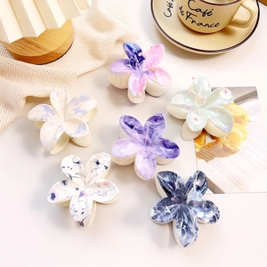 Detail showing various marble pattern flower hair claws with resin finish in a lifestyle setting