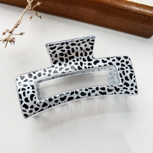 Macro detail of rectangle hair claw clip with black and white spotted leopard print pattern