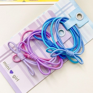 Détail d'élastiques à cheveux avec nœud en tons violet et bleu sur carte support