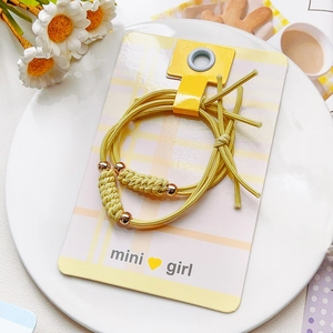 Détail de deux chouchous élastiques jaunes avec perles métalliques sur carte mini