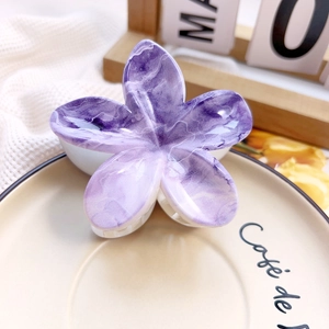Close-up of purple agate textured flower hair claw clip on a ceramic cafe tray