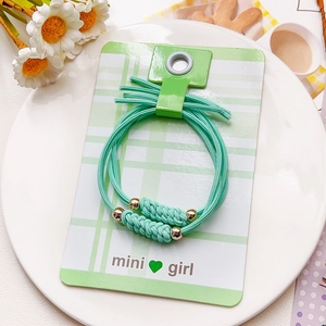 Détail de deux élastiques vert menthe avec billes dorées sur emballage carte mini girl