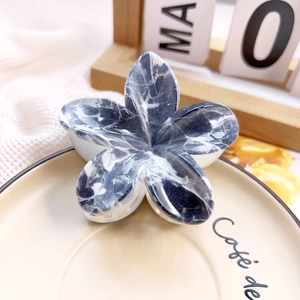 Detail shot of marble textured flower hair claw clip on a decorative ceramic plate