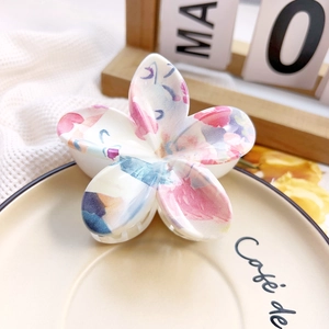 Detail of flower hair claw clip with colorful marble floral patterns on a ceramic tray