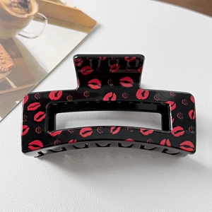 Close-up of black rectangular hair claw clip with red lip pattern on white background