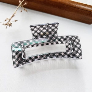 Detail view of pink and black plaid rectangle hair claw clip on white textured surface