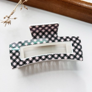 Detail of a rectangular hollow hair claw clip with black and white plaid pattern texture