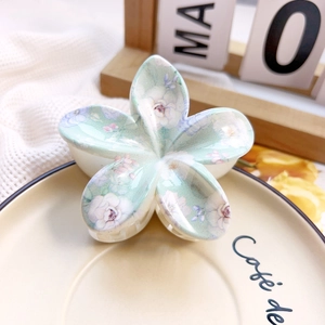 Close-up of marble pattern plumeria hair claw clip on a decorative ceramic tray