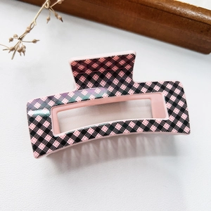 Close-up of pink checkered pattern hair claw clip on a textured white surface